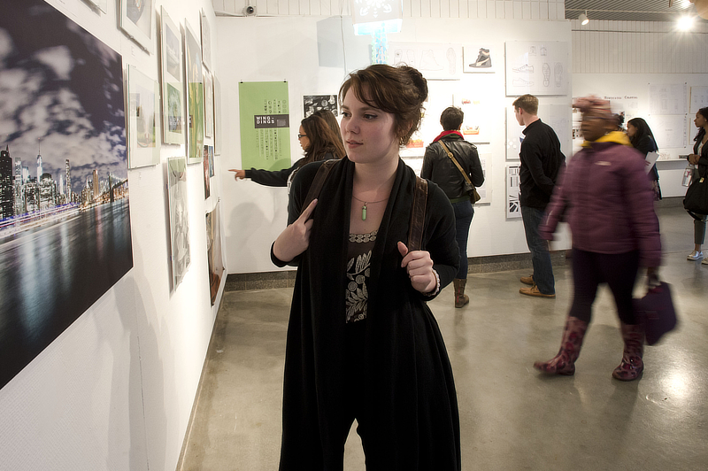 A woman looking at art on a wall in a gallery.