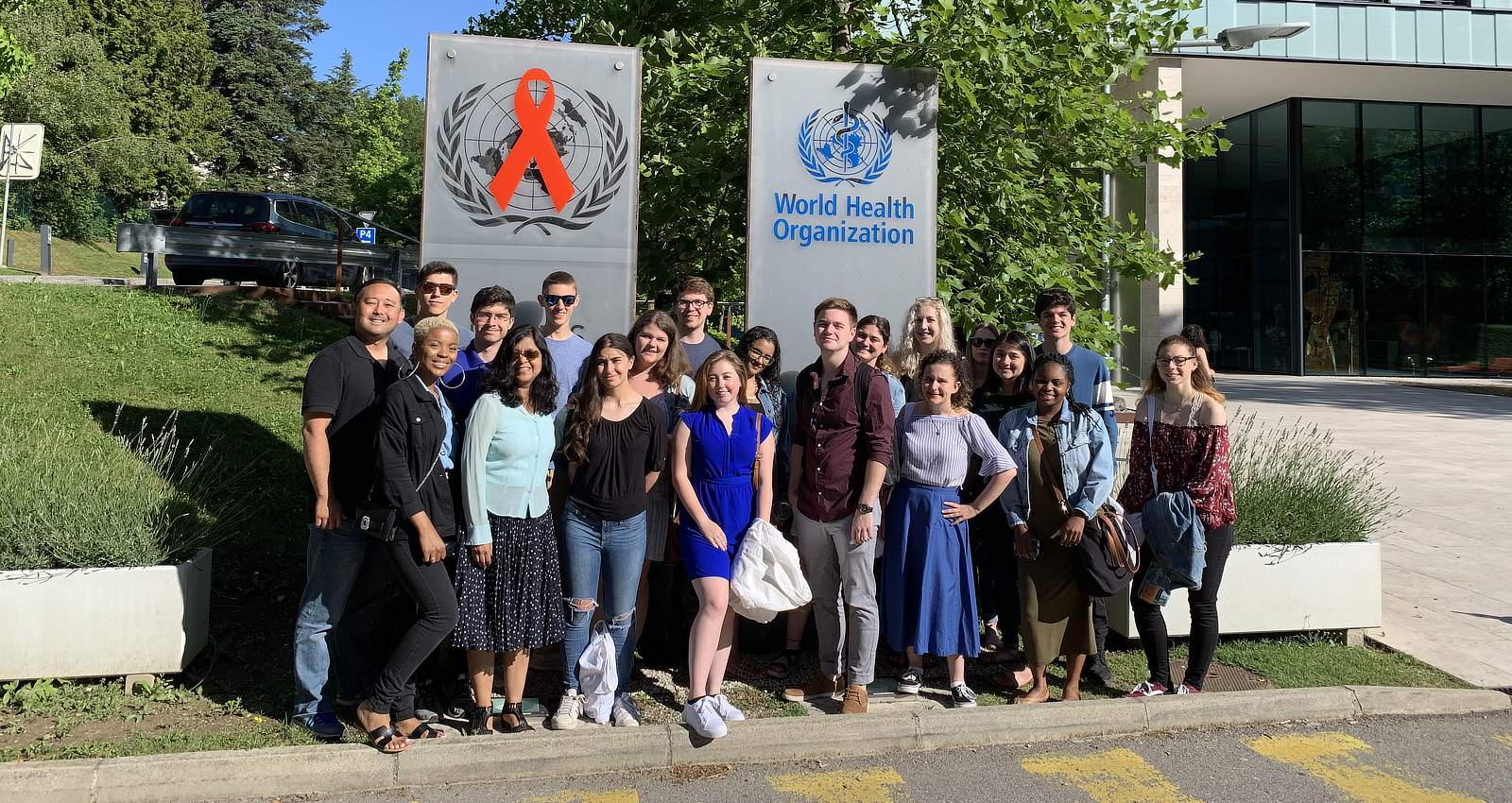 A group of students stands in front of the World Health Organization (WHO).