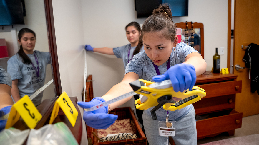 Students measuring in a residence hall room.