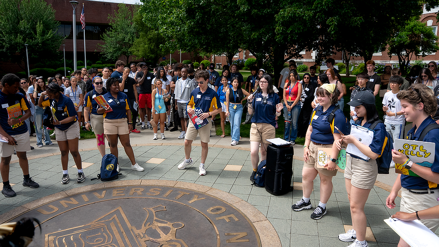 Students sitting in a circle, outside, on campus.