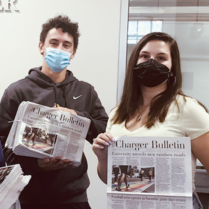 Two students holding up Charger Bulletin newspapers.